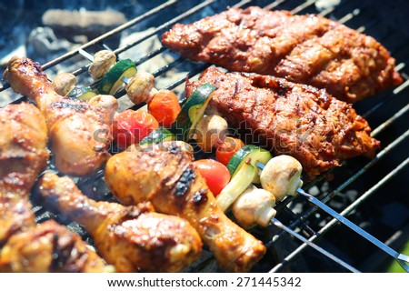 Assorted meat from chicken and pork and various vegetables on barbecue grill cooked for summer family dinner