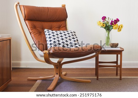 Retro tan leather chair and side table with flowers interior