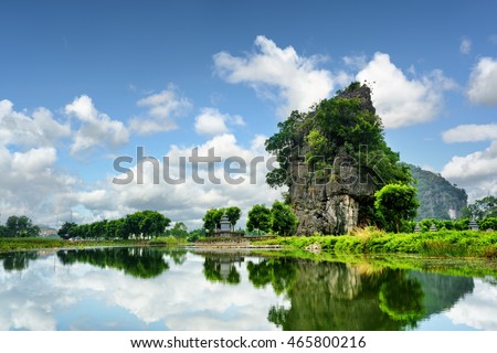 Beautiful natural karst tower reflected in water of the Ngo Dong River at the Tam Coc portion, Ninh Binh Province, Vietnam. The Tam Coc is a popular tourist attraction in Asia.