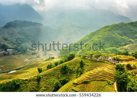 Amazing view of rays of sunlight illuminating green rice terraces through storm clouds at highlands of Sapa District, Lao Cai Province, Vietnam. Sa Pa is a popular tourist destination of Asia.