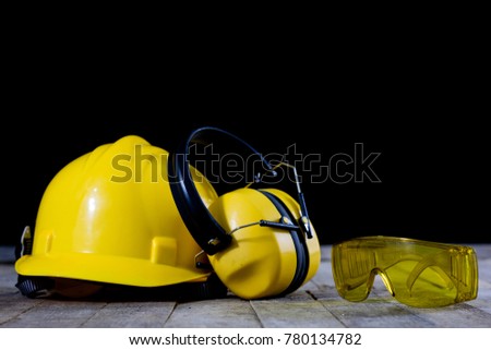 Protective clothing on a wooden workshop table. OSH accessories in the workshop. Black. background.