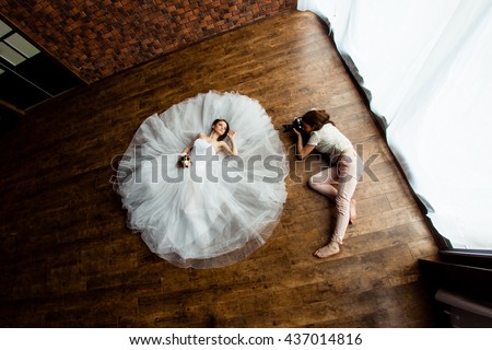 young sexy woman photographer is taking pictures the bride in the studio