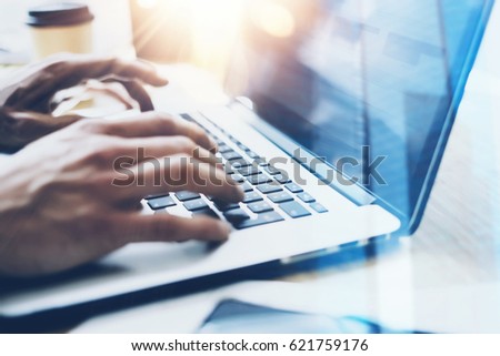 Closeup view of businessman working at sunny office on modern laptop.Male hands typing on notebook keyboard.Blurred background.Sunlight effects