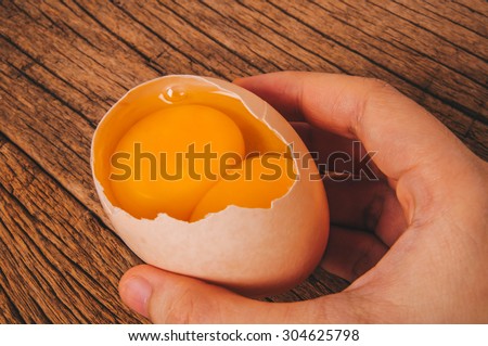Double Yolks Fresh Twin Egg In Shell With Hand Holding On Wood Table Double Yolks Fresh Twin Egg In Shell With Hand Holding On Wood Table