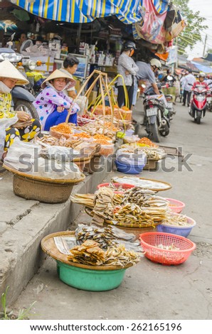 VINH LONG, VIETNAM, JANUARY 3, 2013: Local women sell dried fish and seafood on stalls along the street in Vinh Long market