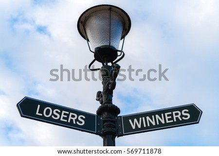 Street lighting pole with two opposite directional arrows over blue cloudy background. Losers versus Winners concept.