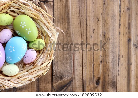 Easter eggs in nest on color wooden background - stock photo