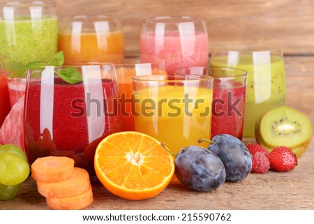 Glasses of tasty fresh juice, on wooden table.