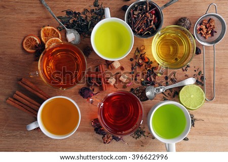 Cups with different kinds of tea and ingredients on table