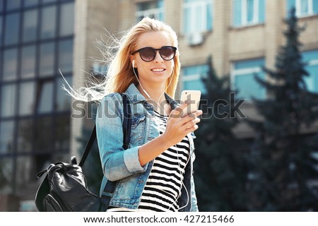https://thumb9.shutterstock.com/display_pic_with_logo/137002/427215466/stock-photo-young-woman-listening-to-music-and-walking-along-the-street-427215466.jpg
