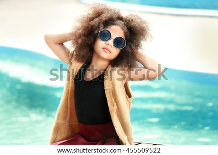 African American little girl wearing stylish clothes by the pool. Fashion kid concept