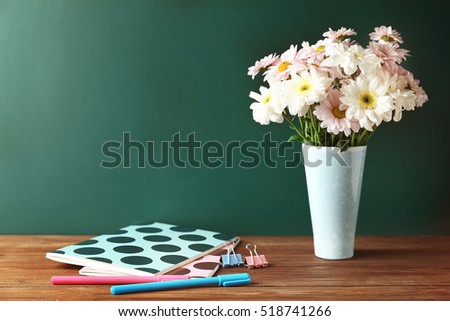 Copybooks and flowers on teacher's desk