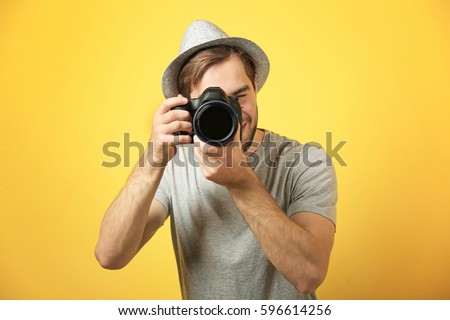 Handsome young photographer on color background