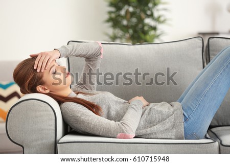 Beautiful young woman suffering from headache at home