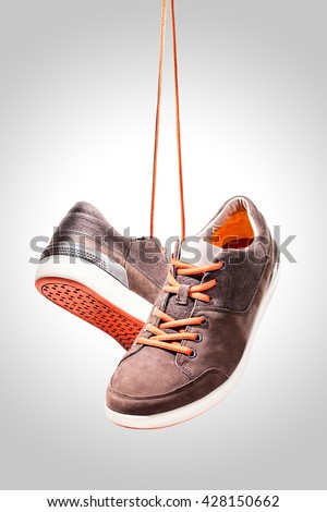 Pair of casual sport leather shoes hanging isolated on white background, Orange shoelace