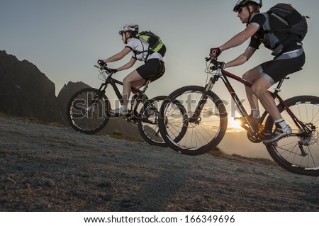 mountainbike - two bikers by uphill mountainbiking on sunset - sunrise
