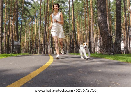 Methods to Impress a Sagittarius Female stock photo young woman running in the park with her dog 529572916