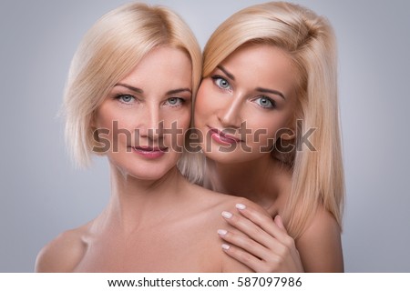 Beautiful middle aged mother and her adult daughter in studio