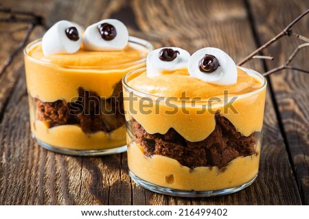 Halloween treats, little monster dessert with chocolate cookies and orange mascarpone cream topped with big marshmallow eyes - stock photo