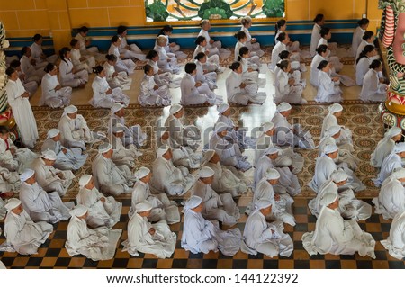 HO CHI MINH, VIETNAM - DEC 24: People praying in Cao Dai Temple on Dec 24, 2012, in Ho Chi Minh, Vietnam. Caodai is a Vietnamese religion mixing different religions from around the world.