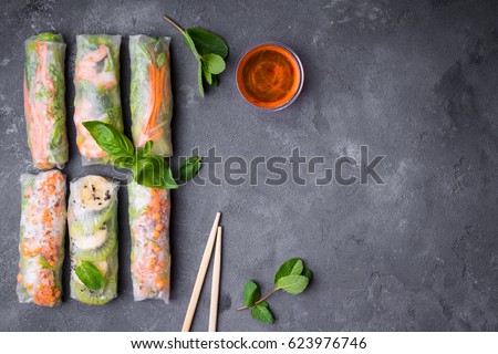 Fresh assorted spring rolls set background. Handmade asian/Chinese spring rolls, sauce, chopsticks. Rustic concrete background. Spring rolls with shrimps, vegetables, fruits. Space for text. Top view
