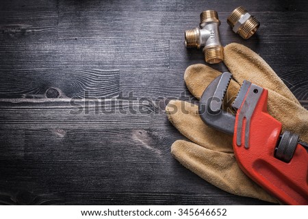 Monkey wrench brass plumbing fittings leather safety gloves construction concept.