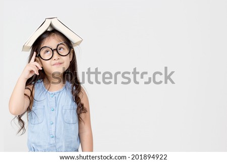 Portrait of little Asian child thinking and put a book on top with copy space