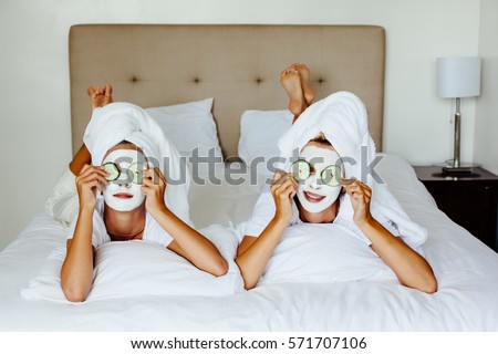 Mom and her 10 years old preteen daughter chilling in the bedroom and making clay facial mask. Mother with child doing beauty treatment together. Morning skin care routine.