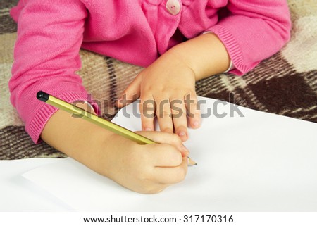 Child writes a pencil on a blank white sheet