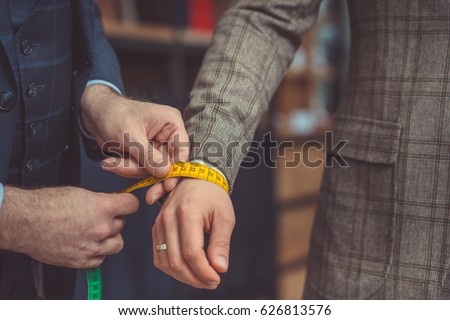 Tailor measures a man's hand