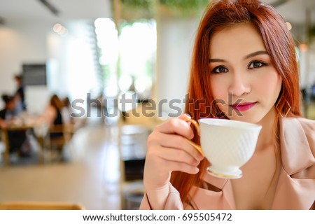 https://thumb9.shutterstock.com/display_pic_with_logo/161178298/695505472/stock-photo-portrait-of-beautiful-woman-holding-a-cup-of-coffee-in-her-hand-in-blur-background-coffee-shop-she-695505472.jpg
