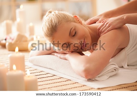 Smiling blond woman enjoying a back massage at a spa centre.