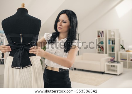 Tailor adjusting a dress on a mannequin at her studio.