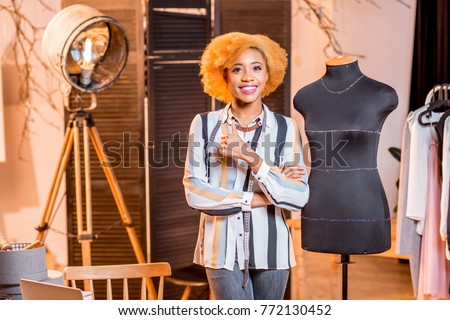 Portrait of a young african fashion designer standing near the mannequin at the studio