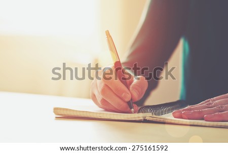 female hands with pen writing on notebook