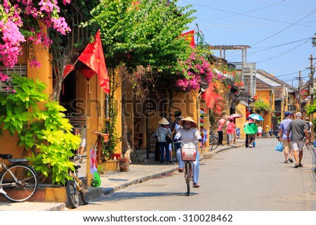 HOI AN, VIETNAM - APIRL 14: An unidentified woman rides her bicycle on Apirl 14, 2014 in Hoi An, Vietnam. Hoi An, a UNESCO World Heritage site, is a major touristic destination in Central Vietnam.