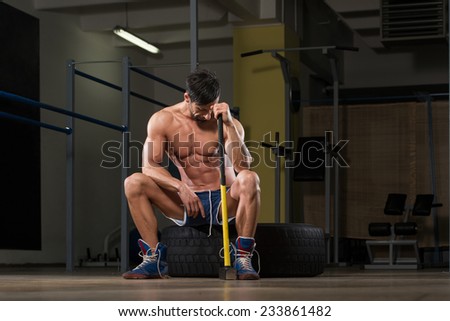 stock-photo-athletic-man-resting-workout-at-gym-with-hammer-and-tractor-tire-233861482.jpg