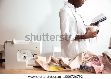 african girl seamstress making notes at notebook. Fashion designer drawing sketches