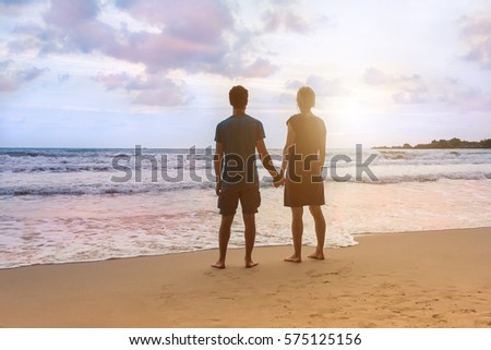 https://thumb9.shutterstock.com/display_pic_with_logo/1638299/575125156/stock-photo-young-couple-is-standing-at-sunset-sea-beach-looking-at-ocean-and-holding-hands-honeymoon-in-575125156.jpg