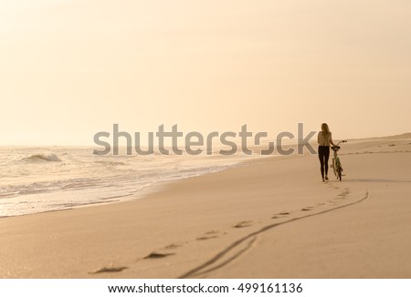 https://thumb9.shutterstock.com/display_pic_with_logo/163856356/499161136/stock-photo-beautiful-blonde-woman-walking-with-her-bicycle-down-a-quiet-beach-at-sunset-499161136.jpg