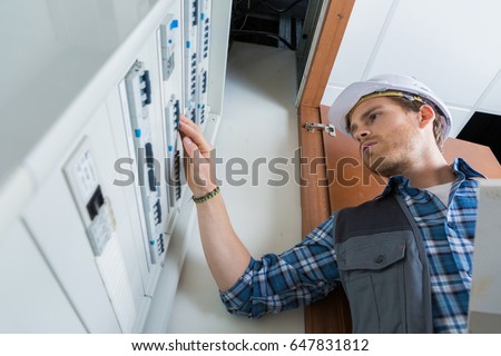 young electrician working on electric panel