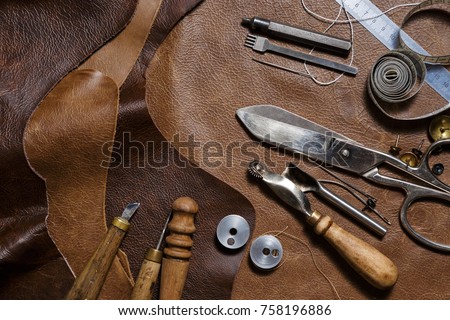 Crafting tools on natural cow leather in the tailoring workshop. Top view.