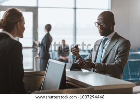 angry businessman giving passport and ticket to staff at airport check in counter