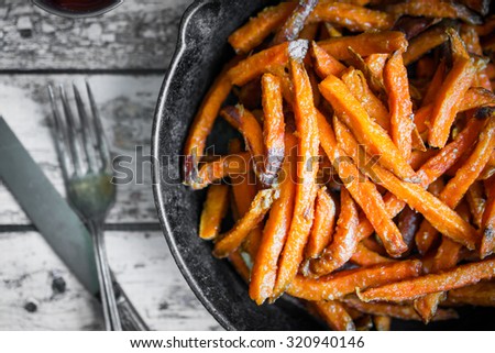 Sweet potato fries in cast iron skillet on wooden background