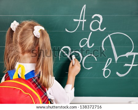 Schoolchild writting on blackboard. Rear view.