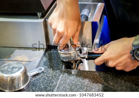 Barista is processing; push the coffee bean in the equipment and tool for make the fresh caffeine drink by coffee machine.