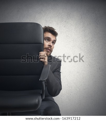 Conceito de medo de um empresário atrás de uma cadeira