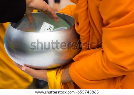 People putting food offerings in alms bowl with Buddhist monk or novice for make merit, Buddhist holy day