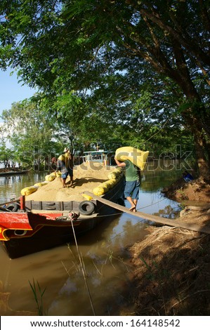 DONG THAP, VIET NAM- NOVEMBER 12: Finish harvest, dealer buy rice of farmer, porter carry rice sack up to boat to transport, rice grain filled hold of boat, Dong Thap, Viet Nam, November 12, 2013
