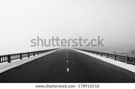 Asphalt road on big bridge cross the lake in fog at morning, the way like arrow, direction to white future, atmosphere full misty